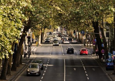 Vierspurige Straße mit Autos umrahmt von Bäumen