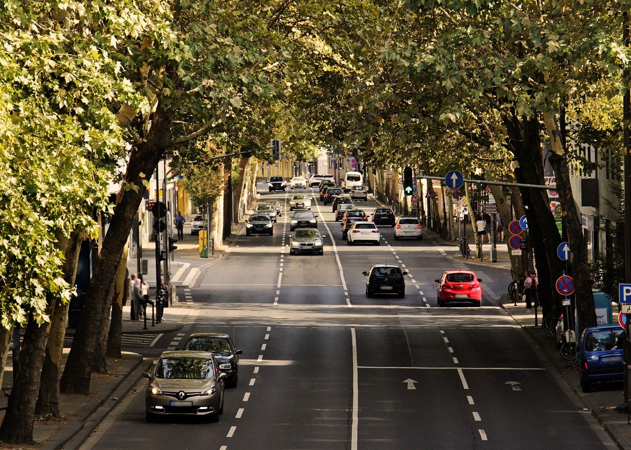 Vierspurige Straße mit Autos umrahmt von Bäumen